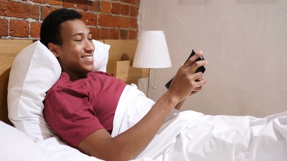 Happy African Man in Bed Checking Wallet with Cash Money