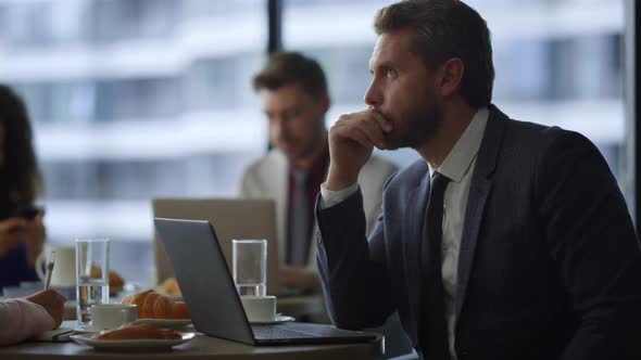 Thoughtful Entrepreneur Working Online with Coworker Colleague in Cafe Office