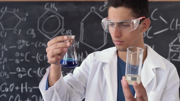 a Male Scientist of Arab Appearance Holds Two Test Tubes in the Laboratory Against the Background of