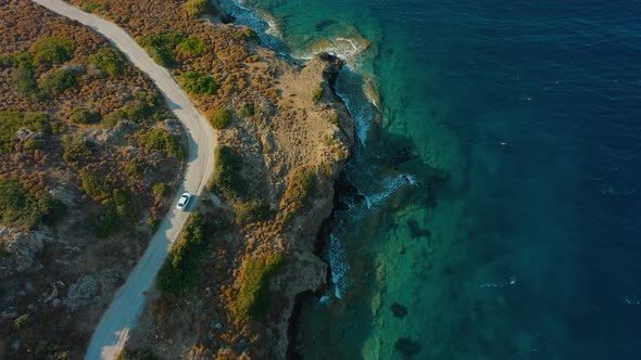 Aerial Top View Car Driving on Coastal Road Sea Waves Washing Rocky Coast