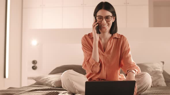 Woman Sitting on Bed Talking on Phone