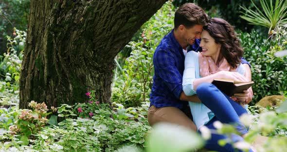 Romantic couple reading novel in park