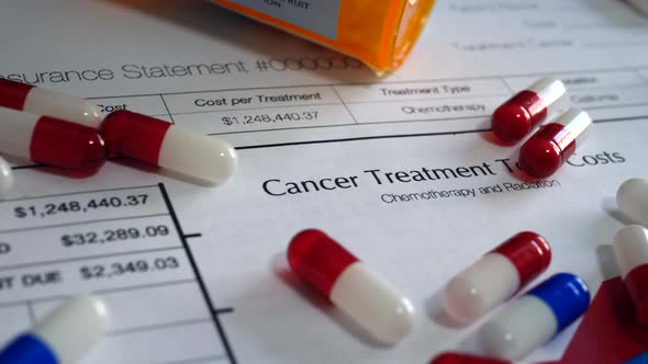 Pills, drugs, and medicine on a prop medical insurance form showing expensive cancer treatment and h