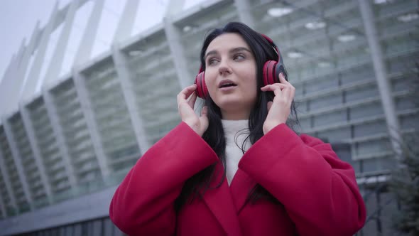 Bottom View of Joyful Caucasian Girl Listening To Music in Headphones and Dancing. Positive