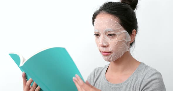 Woman apply paper mask and read book