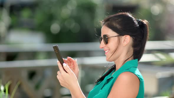 Smiling Adorable Brunette Girl Using Smartphone at Summer Park Having Fun Medium Closeup
