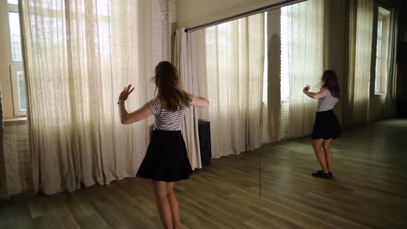 Teenage girl dancing in the studio, next to a mirror reflection in slow motion