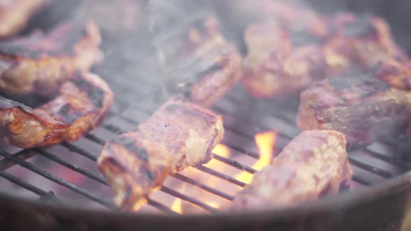 Slow Motion of Sizzling Charred Meat Grilling on Fiery and Smokey BBQ Grill