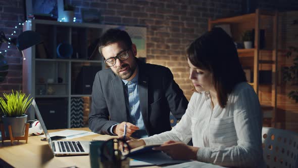 Businesswoman Talking To Man in Office in the Evening Taking Notes Smiling