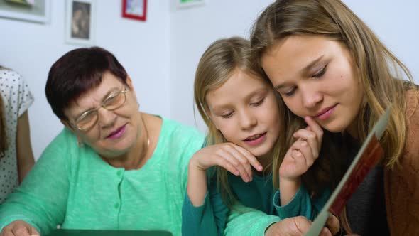 Girls Watch Old Photo Album with Their Grandmother