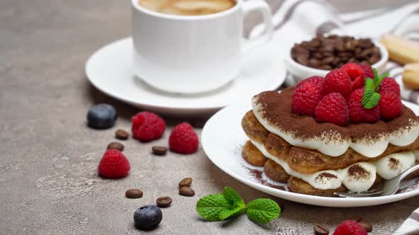 Portion of Classic Tiramisu Dessert with Raspberries and Cup of Coffee on Grey Concrete Background