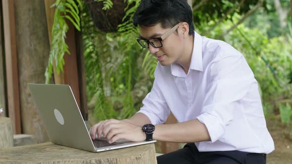 Asian Man Typing On Laptop