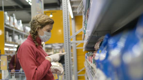 Girl in Mask and Gloves Goes To Shelf with Cereals and Takes Bundles in Hands, Buying Spare Products