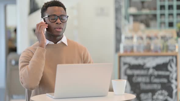 Creative African Man Talking on Phone While Using Laptop