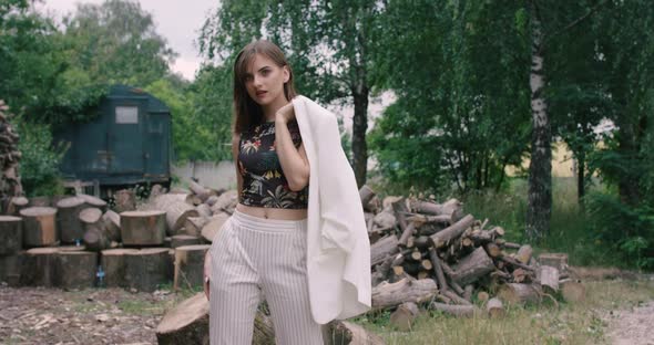 Stylish Model Poses with Jacket and Flirts at Camera on Wood Nature