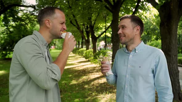 Two Friends Eating Hot Dogs on the Street