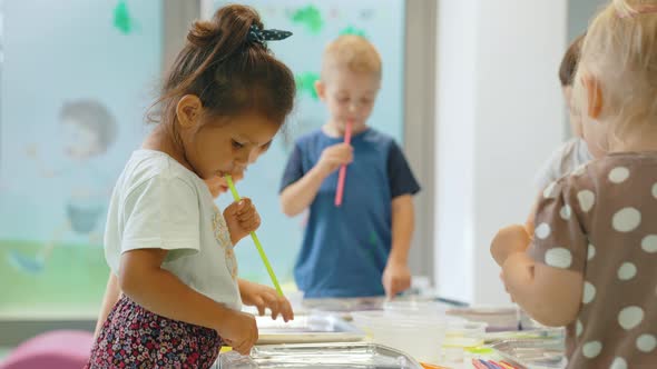 Multiethnic Group of Toddlers Milk Painting with the Teacher Helping Them Using Nontoxic Paint Food