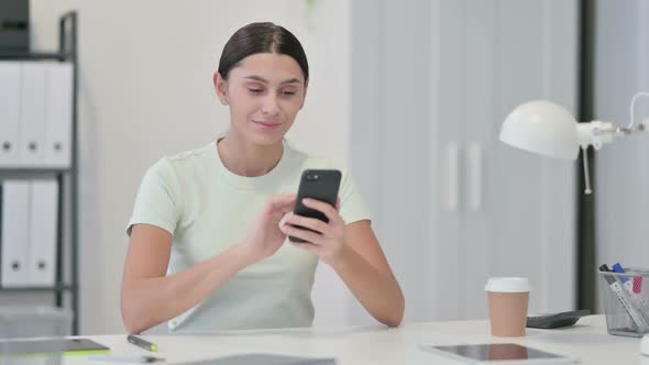 Young Latin Woman Using Smartphone at Work