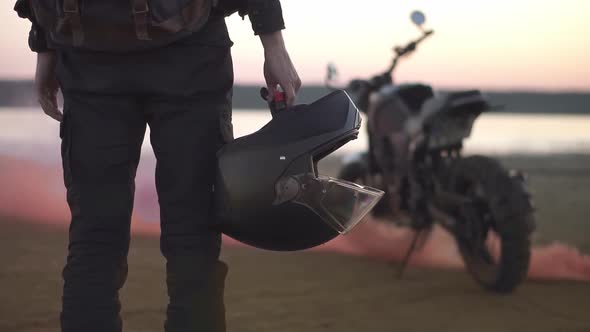 Unrecognizable Biker Stands Looking on His Bike While the Engine is Running and Blowing Out Colored