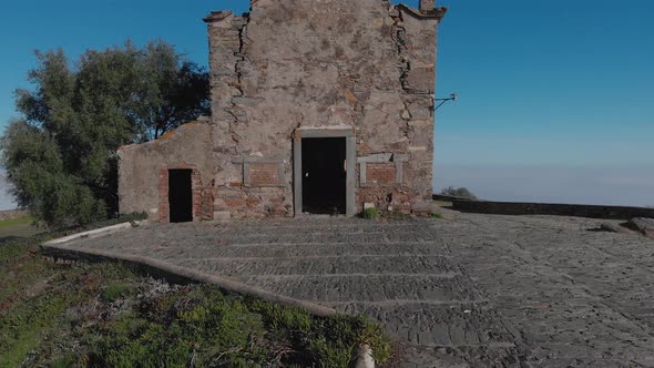 From a doorway, a drone zooms back to reveal an ancient building on the grounds of Monsaraz Castle.