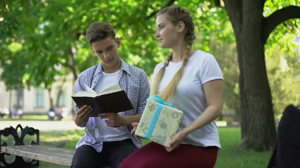 Teen Girlfriend Presenting Birthday Box to Boyfriend in Park, Surprise Present