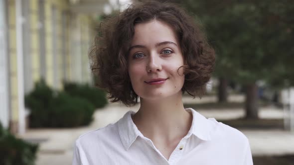 Happy Cheerful Young Woman Wearing A White Shirt. Positive News Or Just Good Mood, Looking At Camera