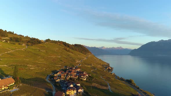 Aerial shot over Riex and Epesses typical villages in Lavaux vineyard at sunset light, autmn colors