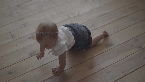 Adorable Baby Girl Crawls on the Floor of the House. Kid Playing at Home. Adorable Happy Child