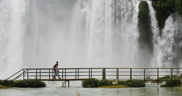 Man Woman Walking Water Bridge Near Beautiful Massive Waterfalls