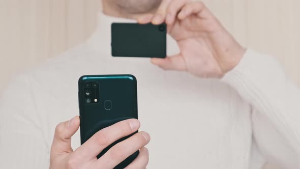 Young Man Uses Smartphone to Scan QR Code on Cold Crypto Wallet for Transaction