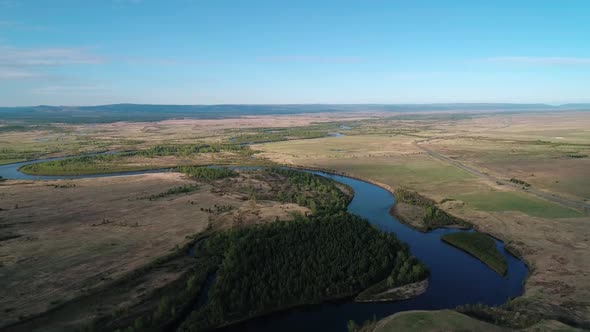 Aerial View of a River Flowing Through Rural Area with Meadows Rare Trees and with the Road on the