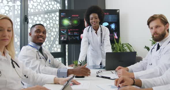 Mixed Race Doctors Pose on Camera with thumbs Up During meeting 