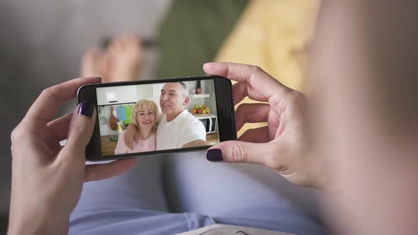 Daughter Woman Talking To Happy Elderly Parents Through Facetime on Smart Phone