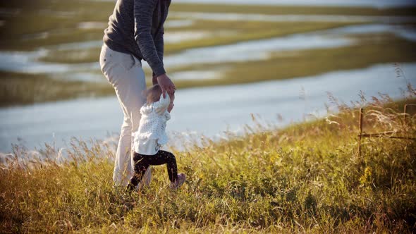 Young Father with His Baby on the Field - Teaching His Daughter How To Walk
