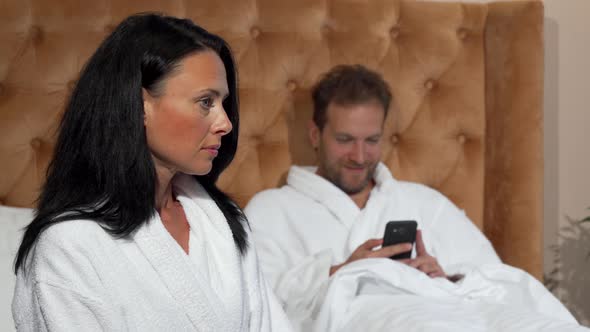 Mature Woman Looking Unhappy While Her Husband Texting on Smart Phone