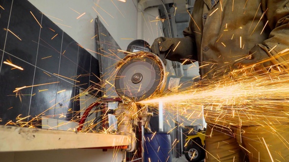 Closeup of worker using a grinder cuts metal in a workshop