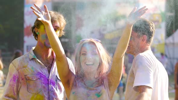 Happy Friends Enjoying Festival of Colors Dancing and Spraying Colored Paint