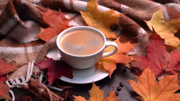 Autumn Fall Leaves Hot Cup of Coffee and Warm Plaid on a Wooden Table Background