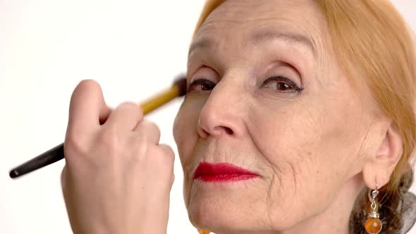 Applying Makeup on Senior Woman.