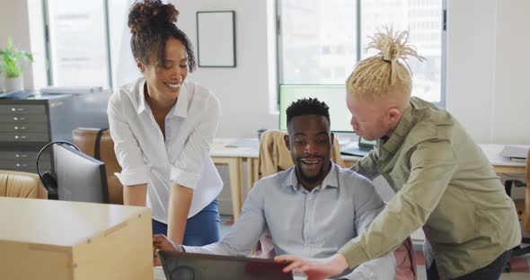 Happy diverse business people discussing with laptop in creative office