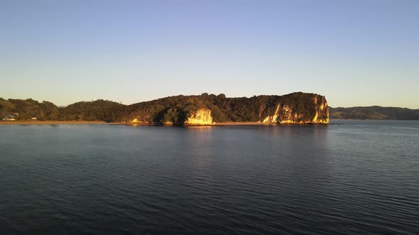 The golden glow of sunrise at the limestone cliffs of Cooks beach