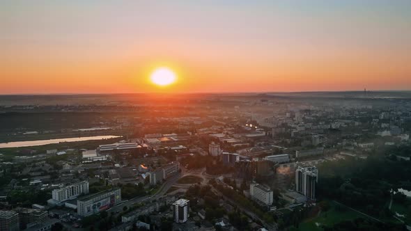 Aerial drone view of Chisinau at sunrise. Multiple buildings, trees, parks, roads with cars, lake. M