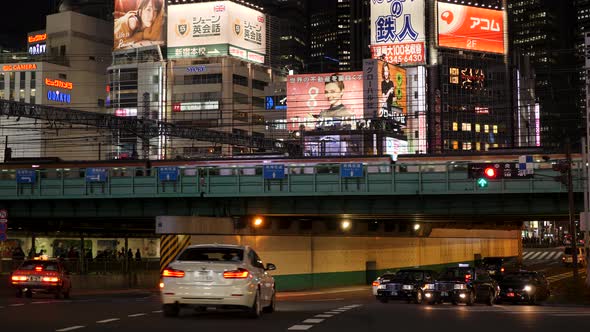 Night View of Busy Tokyo Road in Shinjuku with Lit Up Neon Advertising Screens