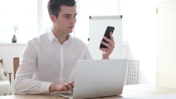 Businessman Working on Laptop and Smartphone in Office