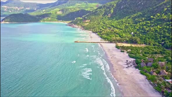 Drone Flies High Above Quiet Ocean Along Wide Coast Beach