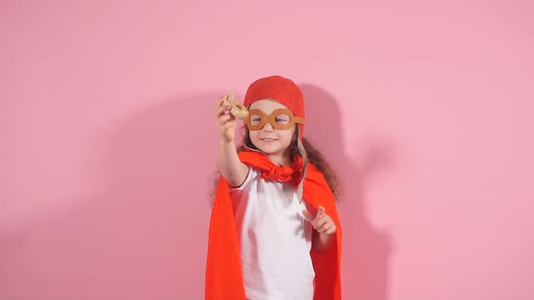 Awesome Girl Child Wearing Red Cloak and Helmet of Pilot Raised Hands Up Holding Wooden Toy Plane