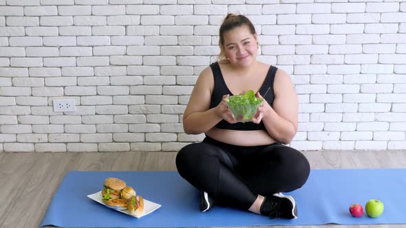 Happy overweight woman in sport wear enjoy eating healthy food after work out at home.