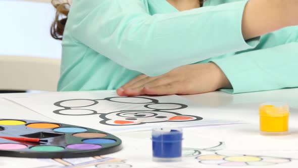 Girl Paints a Children's Figure with Paints and a Brush. Close Up