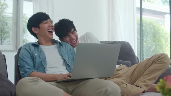 Young Gay couple using computer laptop at modern home.