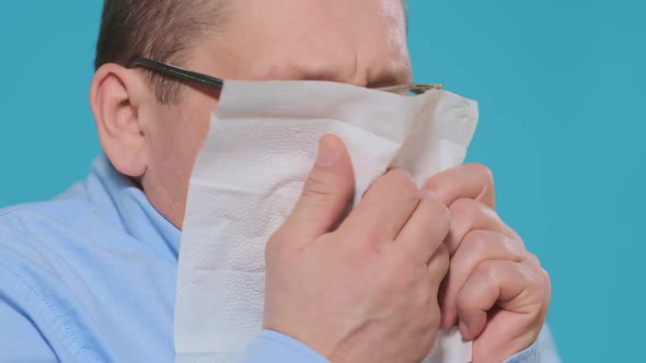 Man Sneezes Into White Paper Napkin